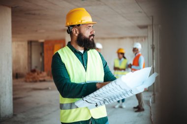Şantiyede çalışan, arka planda bulanık meslektaşları olan, kafkasyalı bir mühendis.