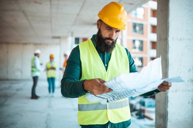 Şantiyede çalışan, arka planda bulanık meslektaşları olan, kafkasyalı bir mühendis.