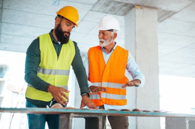 İnşaat alanındaki planlar sırasında konuşan beyaz erkek mühendis veya mimarlar 