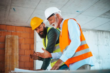 İnşaat alanındaki planlar sırasında konuşan beyaz erkek mühendis veya mimarlar 