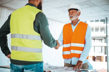 İnşaat alanında erkek mühendisler veya mimarlar el sıkışıyor 