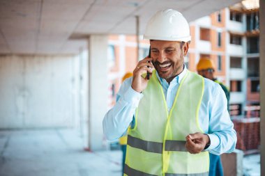 Portrait of man architect at building site. Confident construction manager in formal clothing wearing white hardhat. Successful civil engineer at construction site with copy space. Technology makes my job easier clipart