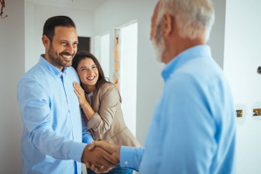 Sevgili evli çift, bir emlakçının yardımıyla yeni bir daire almak istiyorlar. Emlakçı, inşaat halindeki bir evi bir çifte gösteriyor ve onları el sıkışarak selamlıyor.