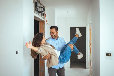 Mutlu ve Heyecanlı Genç Çift, Yeni Alınan ve Kiralanan Dairelerine Bakınıyor. Güzel İnsanlar Mutlu Kucaklaşır. Büyük Parlak Modern Ev. 