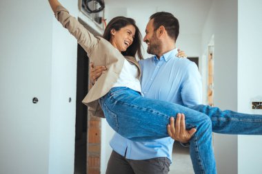 Mutlu ve Heyecanlı Genç Çift, Yeni Alınan ve Kiralanan Dairelerine Bakınıyor. Güzel İnsanlar Mutlu Kucaklaşır. Büyük Parlak Modern Ev. 