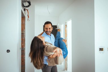 Mutlu çift yeni bir daire aldıkları için mutlu bir şekilde dans ediyorlar. Genç ve neşeli çift evlerinin tadilatı sırasında dans ederken eğleniyorlar..