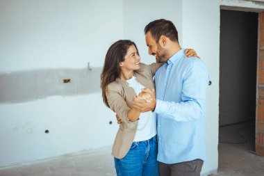 Apartman seçiminde mutlu dans eden çift. Yer değiştirme, emlak, kira konsepti. Mutlu ve heyecanlı genç çift yeni aldıkları şeylere bakınıyor.