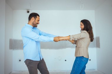 Apartman seçiminde mutlu dans eden çift. Yer değiştirme, emlak, kira konsepti. Mutlu ve heyecanlı genç çift yeni aldıkları şeylere bakınıyor.