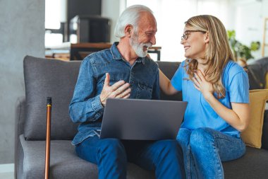 Özürlü bir adam sosyal hizmet görevlisiyle birlikte internet üzerinden fatura ödemeyi öğreniyor. Hemşire dizüstü bilgisayarla çalışan yaşlı emeklilere yardım ediyor. Aktif kıdemli bir adam dizüstü bilgisayar kullanıyor. Kadın bakıcısı evdeki kanepede oturuyor.