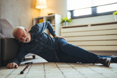 Yaşlı hasta yaşlı adam yerde yatıyor çünkü salonda tahta bastonla tökezledi yaşlı adam dedesi bastonla yürürken kaza yaptı.