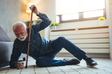 Yaşlı hasta yaşlı adam yerde yatıyor çünkü salonda tahta bastonla tökezledi yaşlı adam dedesi bastonla yürürken kaza yaptı.