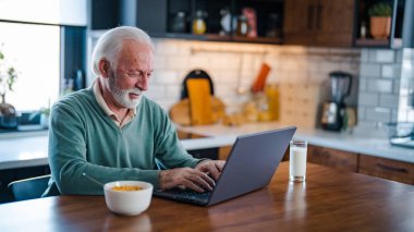 Kahve ve kahvaltı yaparken dizüstü bilgisayarda çalışan yakışıklı bir girişimci. Mutfak masasında dizüstü bilgisayar kullanan yaşlı bir adam. Bilgisayar, para ve mutfakta yaşlı bir erkek emekliyle iletişim.