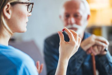 Kadın doktor evdeki yaşlı erkek hastaya reçete yazıyor. Kadın pratisyen hekim şişesi hapları olgun bir müşteriye reçeteli ilaç veriyor. Yaşlılar için sağlık hizmeti kavramı.