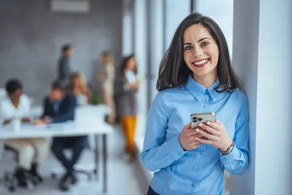Shot of a young businesswoman using a cellphone in an office. Shot of an attractive young businesswoman using a smartphone in a modern office. Smiling business woman in casuals talking on phon