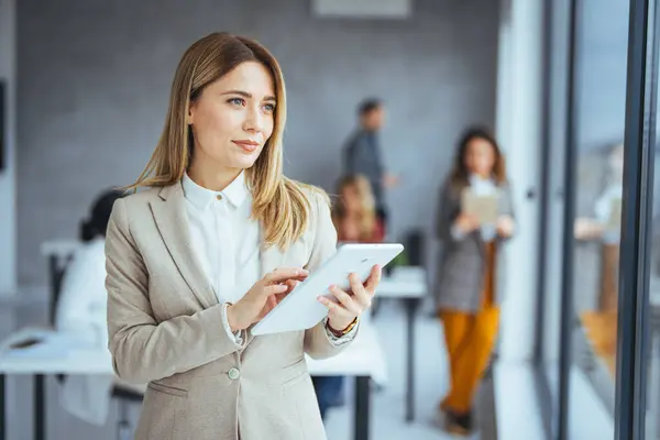 Shot of a businesswoman holding a digital tablet while standing in the boardroom. Portrait of a successful business woman using digital tablet. Young attractive female manager working on digital tablet