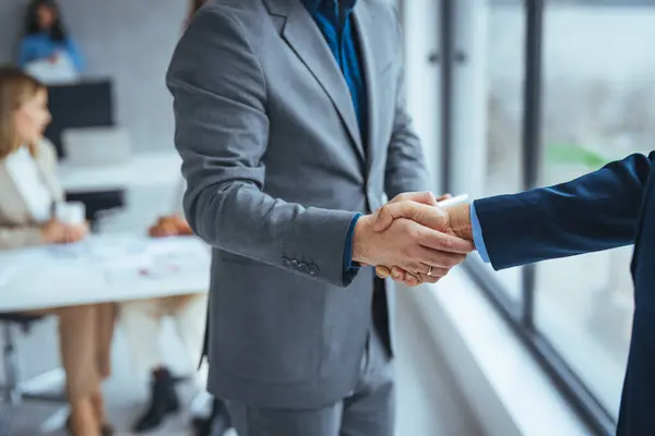 Good deal. Close-up of two business people shaking hands while sitting at the working place. Bussiness,working, success concept. Portrait of manager handshake with new employee.