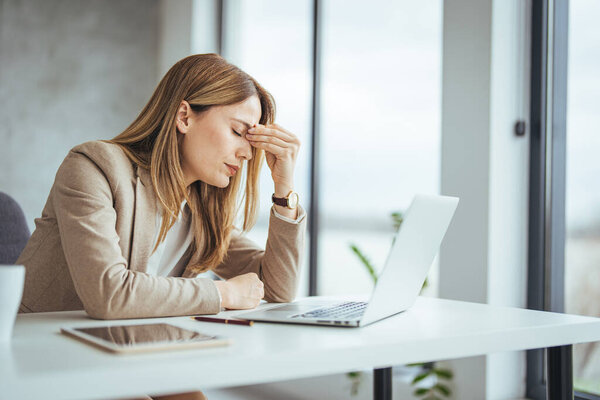 Застрелен молодой предпринимательницей, выглядящей напряженной во время работы в офисе. Стрессовая деловая женщина, работающая с ноутбука выглядит взволнованной, уставшей и подавленной 