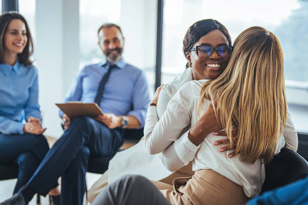 Групповая терапия, концепция эмпатии, психологическая поддержка, разнообразные друзья преодолевают проблемы вместе, лечение зависимости или сплочение команды. Пациенты группы поддержки обнимаются во время сеанса терапии 