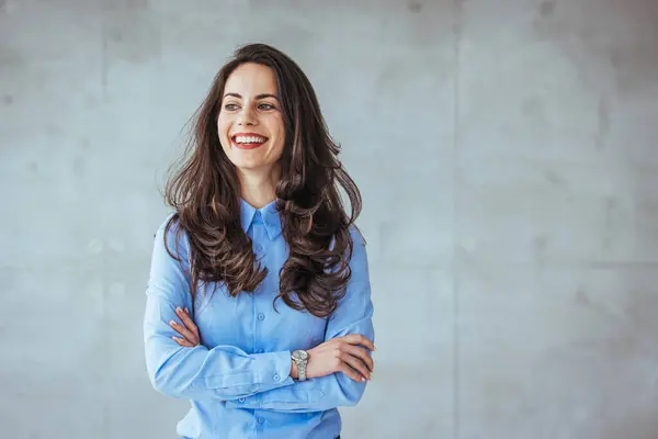 Image of happy young business woman posing isolated over grey wall background. Smiling Pretty Business Woman With Arms Crossed. Portrait of middle aged businesswoman in modern office looking at camera