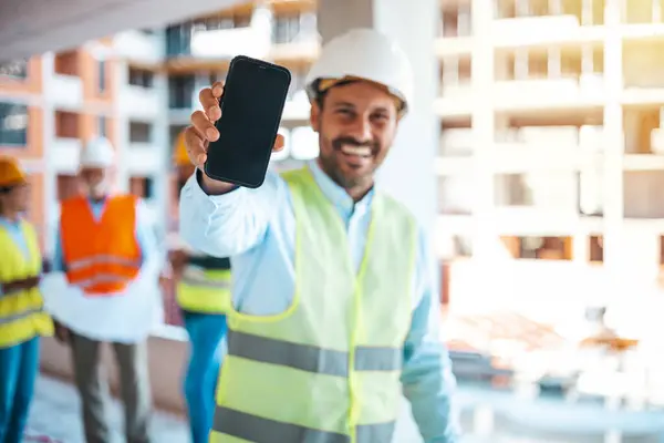 Inżynier Trzymający Plany Pokazujący Smartfona Mężczyzna Inżynier Budowlany Demonstruje Swój — Zdjęcie stockowe