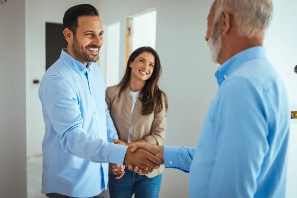 Happy couple buying a new home and handshaking with their real estate agent. Estate Agent Greeting Couple During Visit To New Home. Couple house property agent home real estate business buying investment