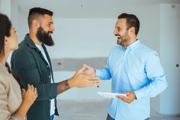 Happy couple buying a new home and handshaking with their real estate agent. Estate Agent Greeting Couple During Visit To New Home. Couple house property agent home real estate business buying investment
