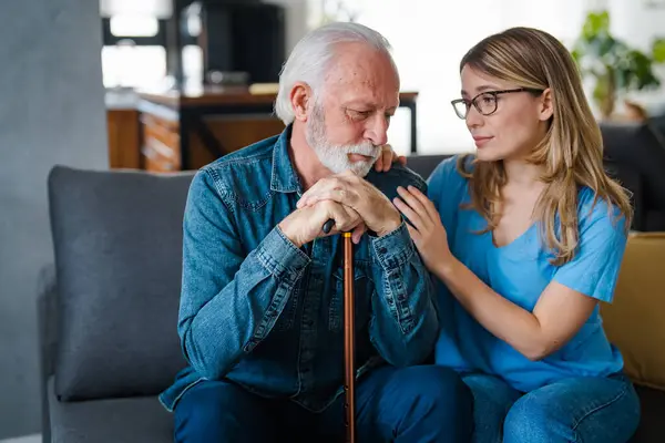 Attentive young lady physician interview senior patient on meeting listen to complaints make diagnosis. Stressed sad elderly man visit trusted capable doctor feel headache dizzy problems with memory