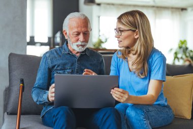 Nurse help senior man with internet and laptop on the sofa in a retirement home. Healthcare worker, caregiver or medical professional helping retired man with email and technology in the lounge