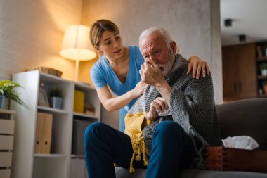 Evde kanepede peçeteli yaşlı bir adam hastalıkla ilgileniyordu.