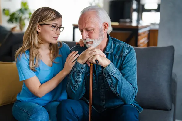 Attentive young lady physician interview senior patient on meeting listen to complaints make diagnosis. Stressed sad elderly man visit trusted capable doctor feel headache dizzy problems with memory
