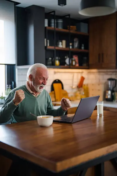 Happy excited old elderly man winner excited by reading good news looking at laptop, overjoyed senior mature grandfather watching game online celebrating goal bid bet win great result victory concept