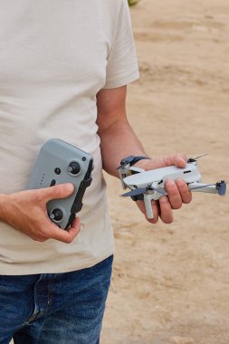 Genç bir adam elinde bir dron ve uzaktan kumanda tutuyor.