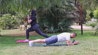 Bir çift parkta paspasın üzerinde spor yapıyor. Spor salonu açık havada..