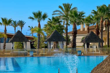 Otel kompleksinin yanındaki havuzun yanında güneşli boş çardaklar misafirlerin beklentisiyle.