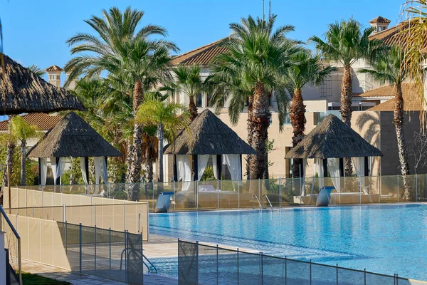 Otel kompleksinin yanındaki havuzun yanında güneşli boş çardaklar misafirlerin beklentisiyle.