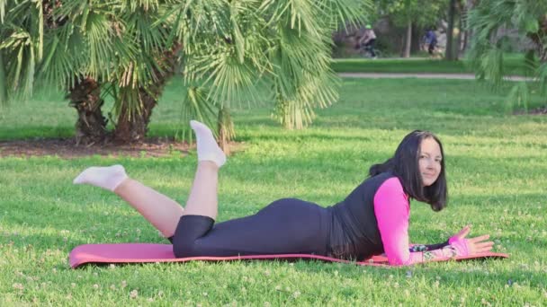 屋外の公園でフィットネスマットを練習した後に休んでいる中年の白人女性 健康的なアクティブライフスタイル — ストック動画