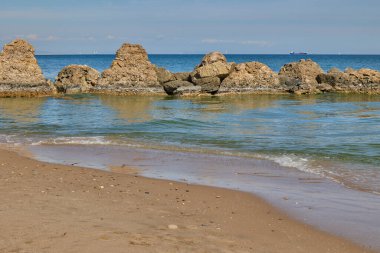 Mavi deniz, bulutlu mavi gökyüzü ve yüksek taşlar. Balear Denizi, İspanya.