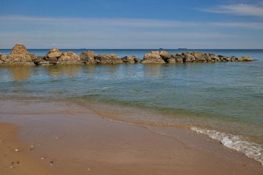 Mavi deniz, bulutlu mavi gökyüzü ve yüksek taşlar. Balear Denizi, İspanya.