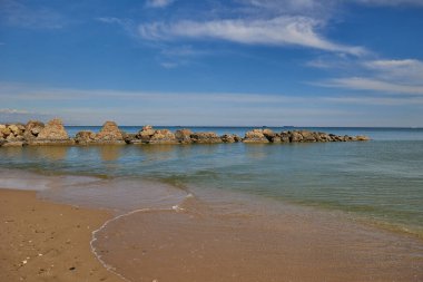 Mavi deniz, bulutlu mavi gökyüzü ve yüksek taşlar. Balear Denizi, İspanya.