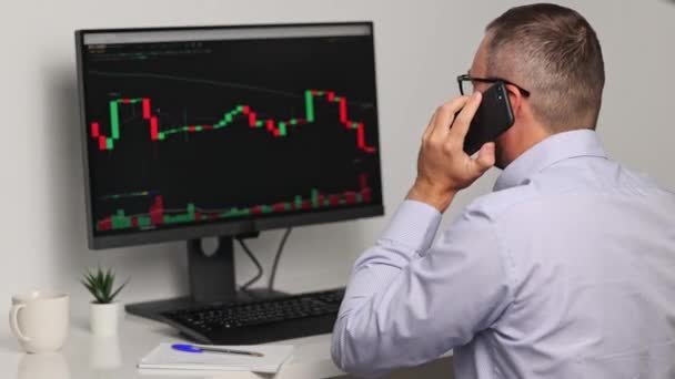 Közelkép Arról Kereskedőről Aki Figyeli Befektetéselemzéseket Monitor Képernyőjén Telefonon Beszél — Stock videók