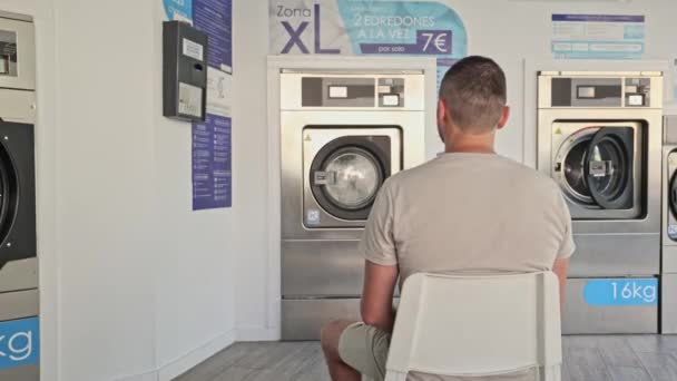 Rückansicht Eines Mannes Der Waschsalon Sitzt Und Darauf Wartet Dass — Stockvideo