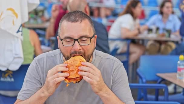 Young Man Glasses Eats Small Burger — Stock Video
