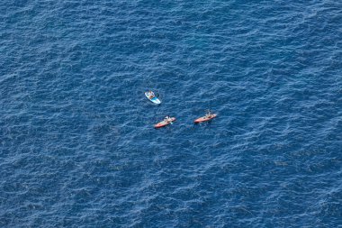 Granadella plajı, Javea, Alicante, İspanya - 12 Ağustos 2023: 3 kişi denizdeki SUP tahtalarında oturuyor.