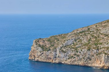 İspanyol Akdeniz manzaralı kıyı şeridi. Deniz koyuna çıkan kayanın görüntüsü. Uçurumun kenarındaki eski bir kalenin kalıntıları. Granadella Plajı, Costa Blanca, İspanya.