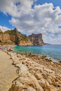 Cala del Moraig plajı, Benitatxell, Alicante, İspanya - 13 Ağustos 2023: Kayalıkların, mavi gökyüzünün ve gök mavisi Akdeniz 'in olduğu bir körfezdeki güzel sahil.
