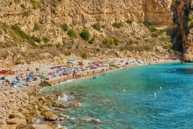 Cala del Moraig plajı, Benitatxell, Alicante, İspanya - 13 Ağustos 2023: Kayalıkların, mavi gökyüzünün ve gök mavisi Akdeniz 'in olduğu bir körfezdeki güzel sahil.