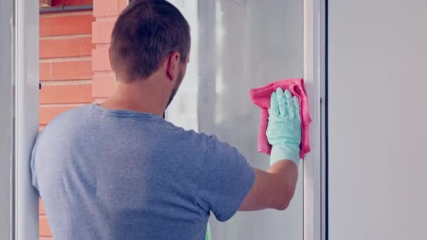 ハウスクリーニング ゴム製手袋の白人男性は スプレーと赤いナプキンを使用して窓のガラスをきれいにします — ストック動画