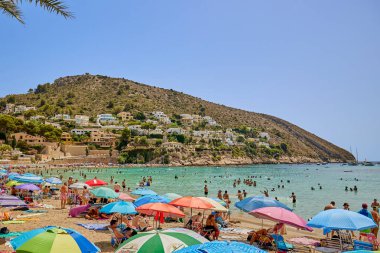 El Portet plajı, Moraira, Alicante, İspanya - 15 Ağustos 2023: İspanya 'nın Cala El Portet, Kosta Blanca bölgesi olarak da bilinen temiz turkuaz suyu olan küçük ve güzel bir kumlu sahil manzarası.
