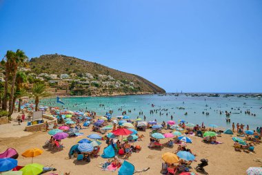 El Portet plajı, Moraira, Alicante, İspanya - 15 Ağustos 2023: İspanya 'nın Cala El Portet, Kosta Blanca bölgesi olarak da bilinen temiz turkuaz suyu olan küçük ve güzel bir kumlu sahil manzarası.