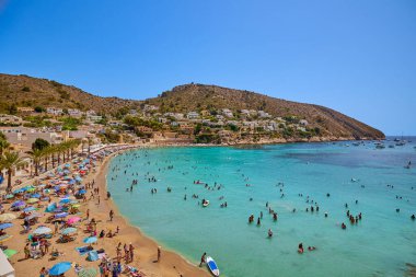 El Portet plajı, Moraira, Alicante, İspanya - 15 Ağustos 2023: İspanya 'nın Cala El Portet, Kosta Blanca bölgesi olarak da bilinen temiz turkuaz suyu olan küçük ve güzel bir kumlu sahil manzarası.